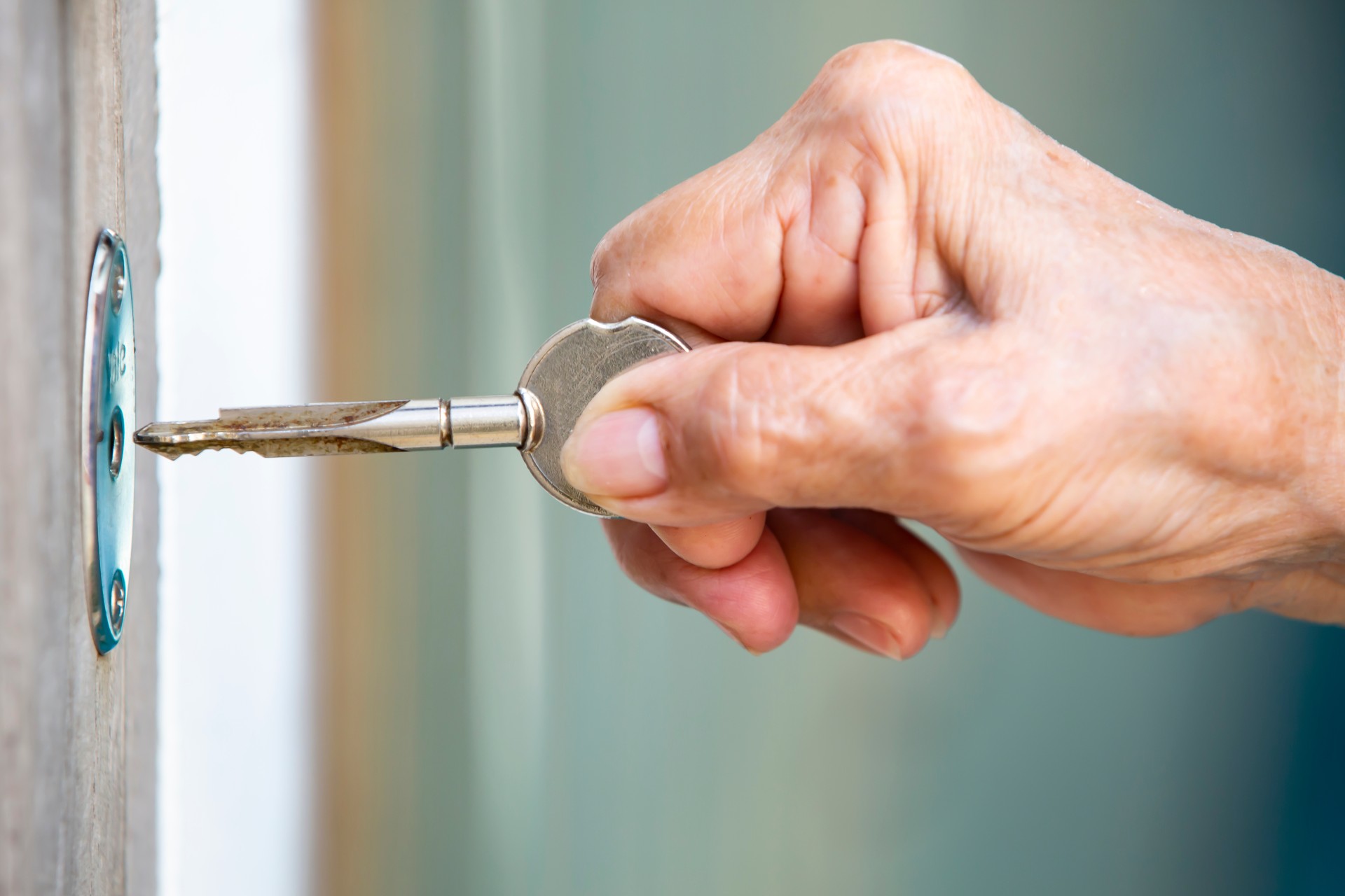 shutterstock_1350640115 Senior woman's hand locking a door