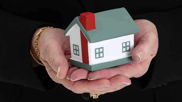 downsizing-blog a pair of older hands holding a small white house