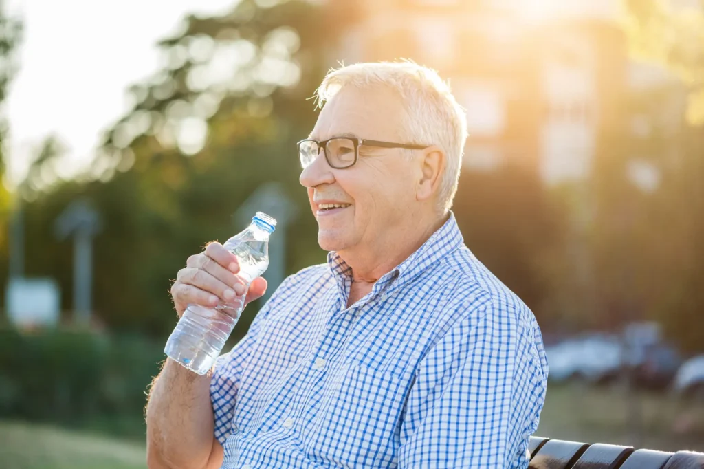 Senior man drinking water after reading about dehydration in older adults Senior man drinking water after reading about dehydration in older adults