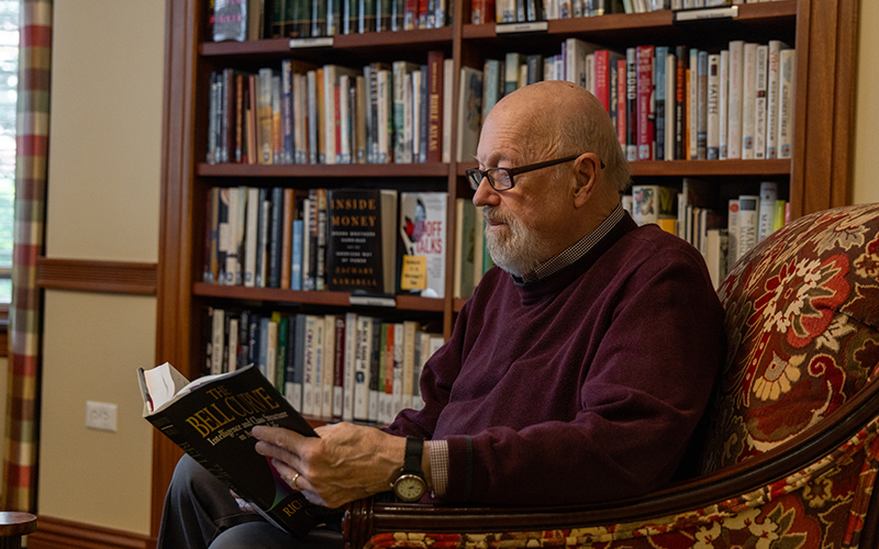 Senior man reading a book in the library at Lake Forest Place