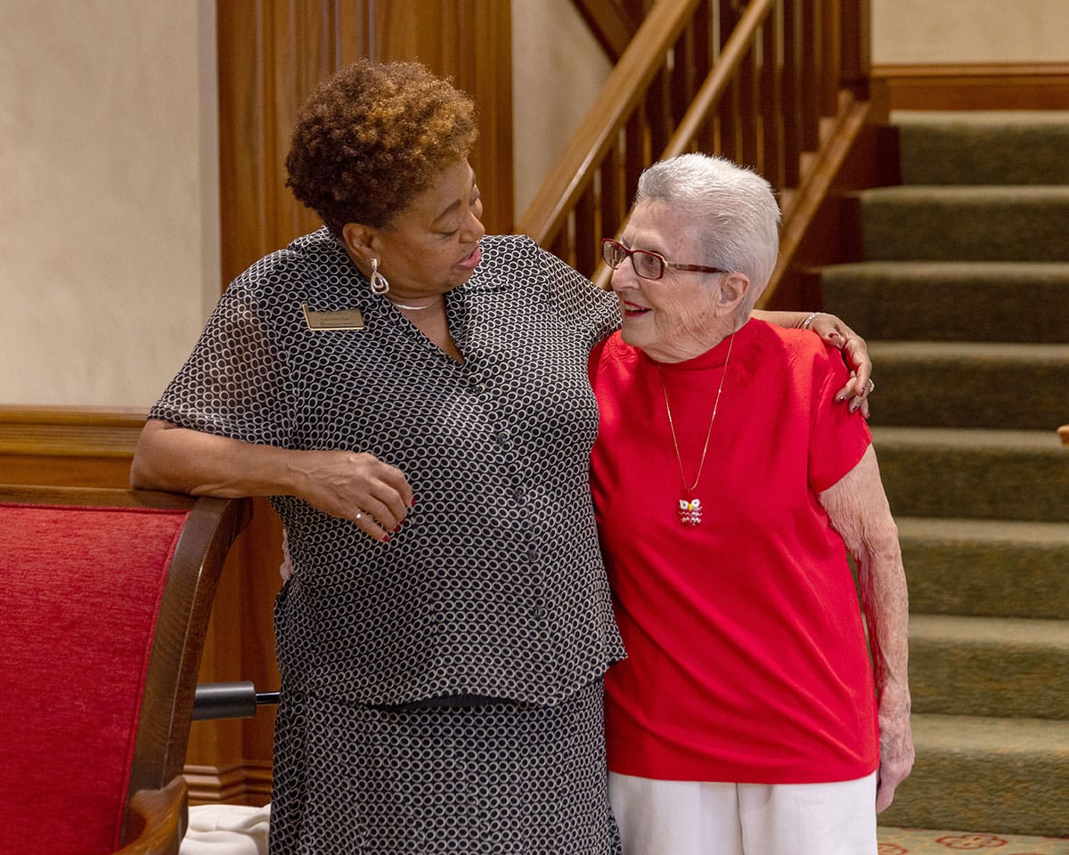 Resident at Lake Forest Place being hugged by her caregiver