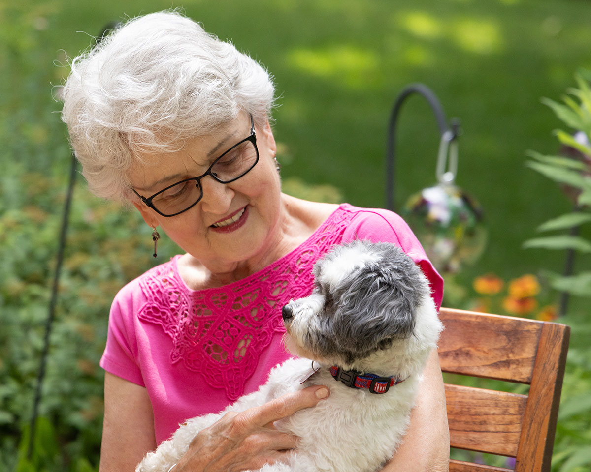 Resident cuddling with her dog outside at Lake Forest Place
