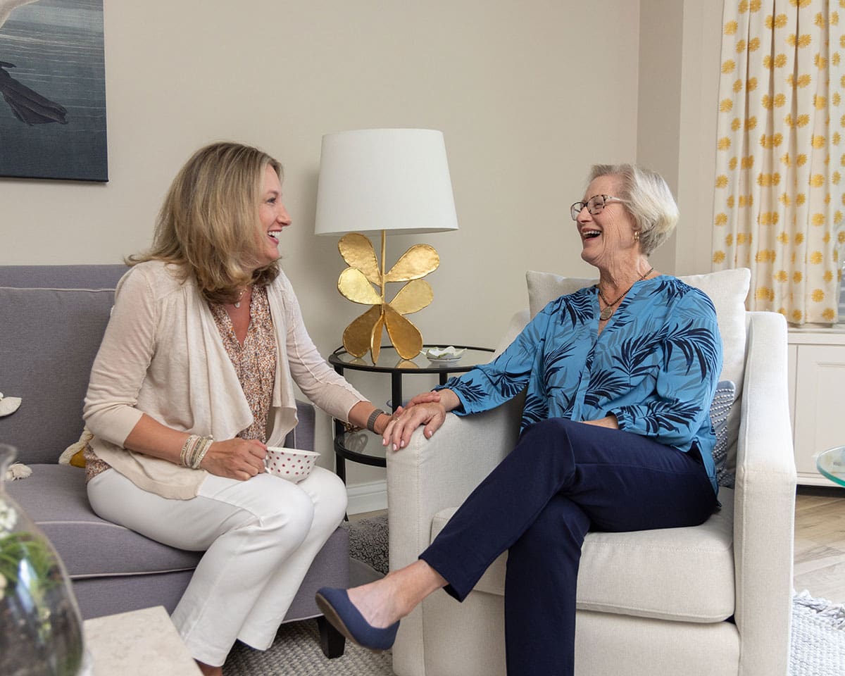 Resident sitting in her apartment at Lake Forest Place and chatting with her adult daughter