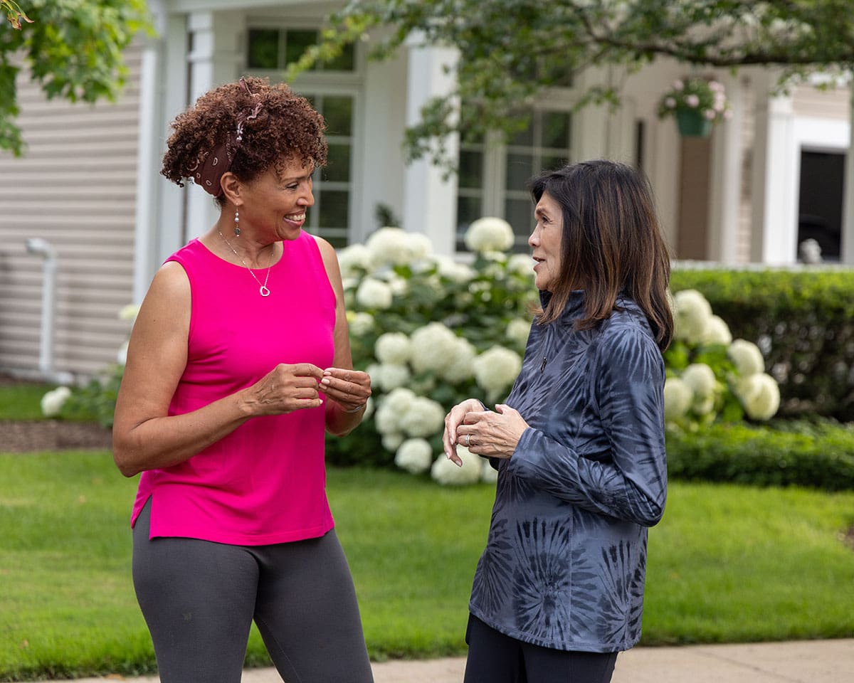 Two resident women taking a break from jogging outdoors at Lake Forest Place to chat with each other