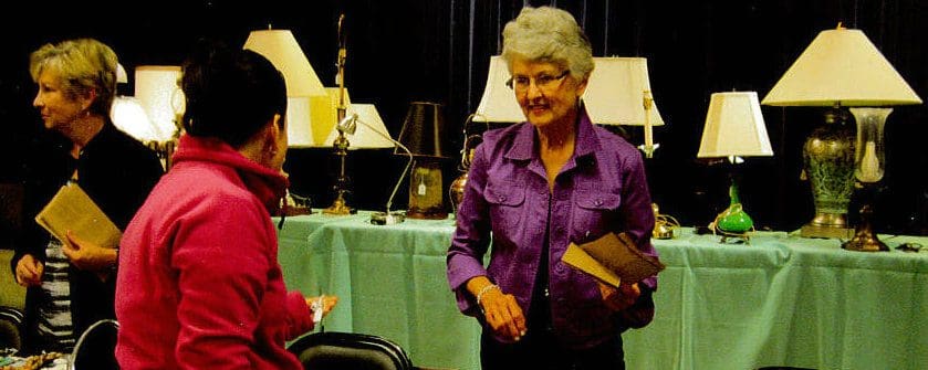 Lake Forest Place Residents Support Employees Through Dollars for Our Scholars Program senior woman at a table selling trinkets and miscellaneous items