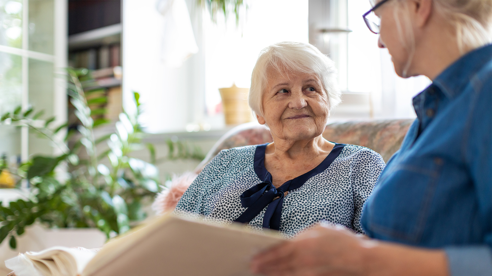 Memory Care patient smiling while sitting with her caregiver Memory Care patient smiling while sitting with her caregiver