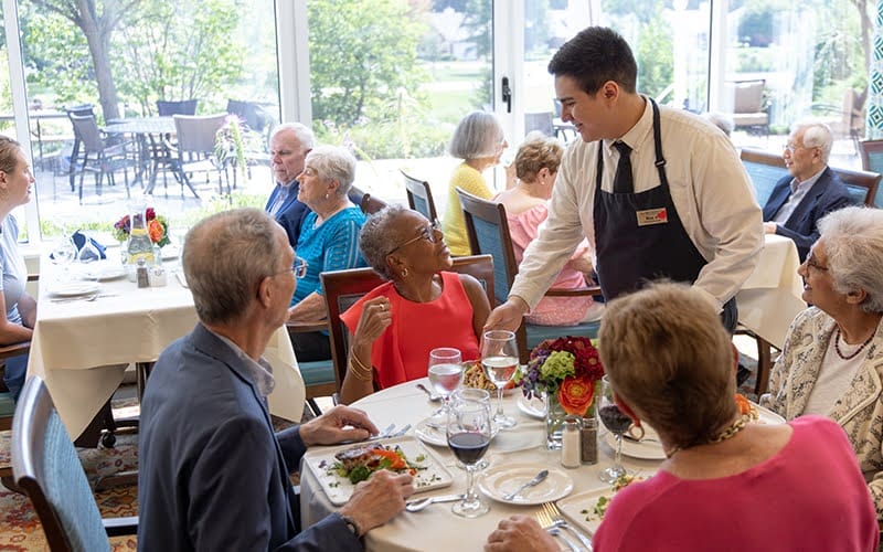 Group of residents enjoying a meal in the dining room at The Moorings of Arlington Heights