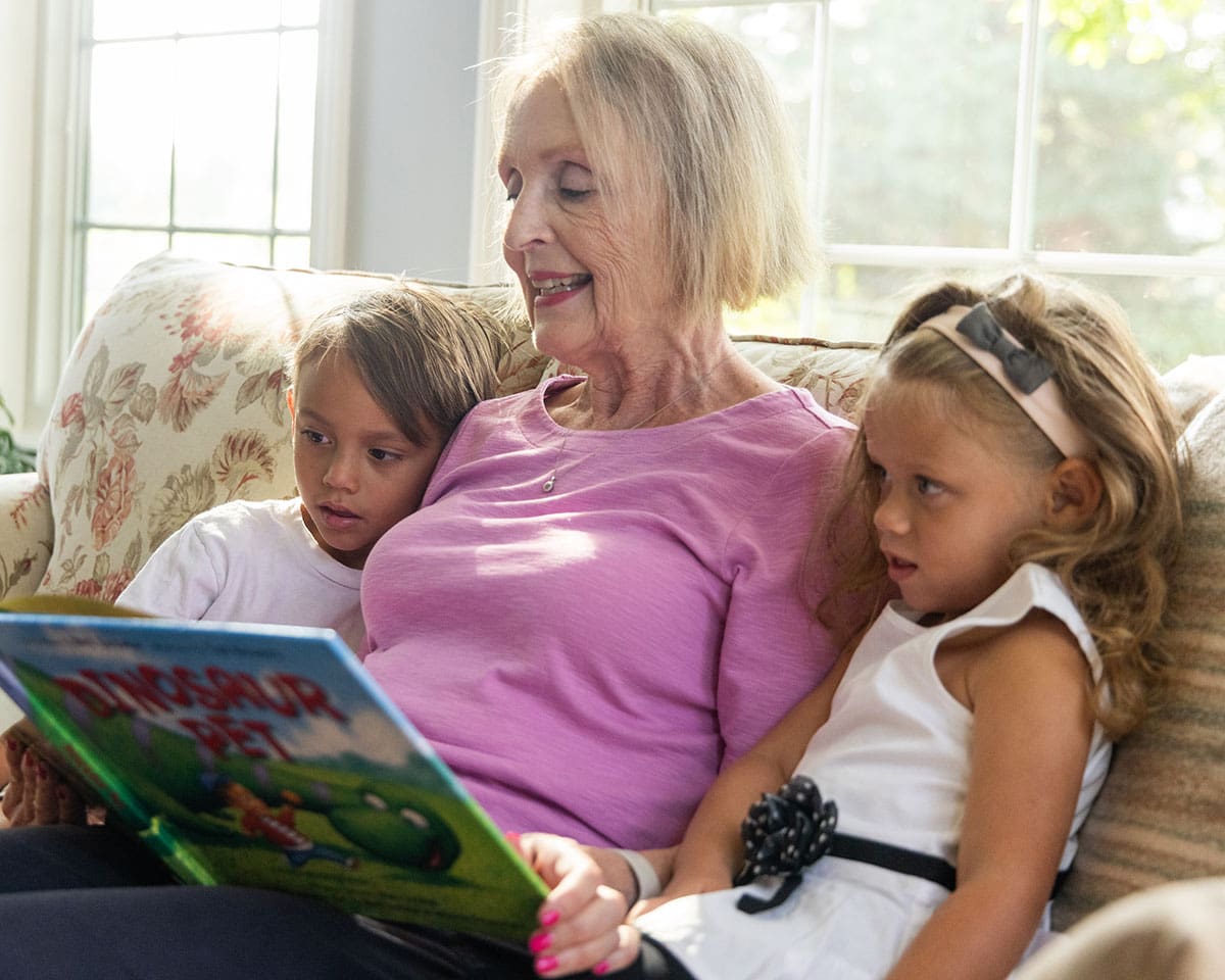 Resident reading to her grandchildren in her apartment home at The Moorings of Arlington Heights