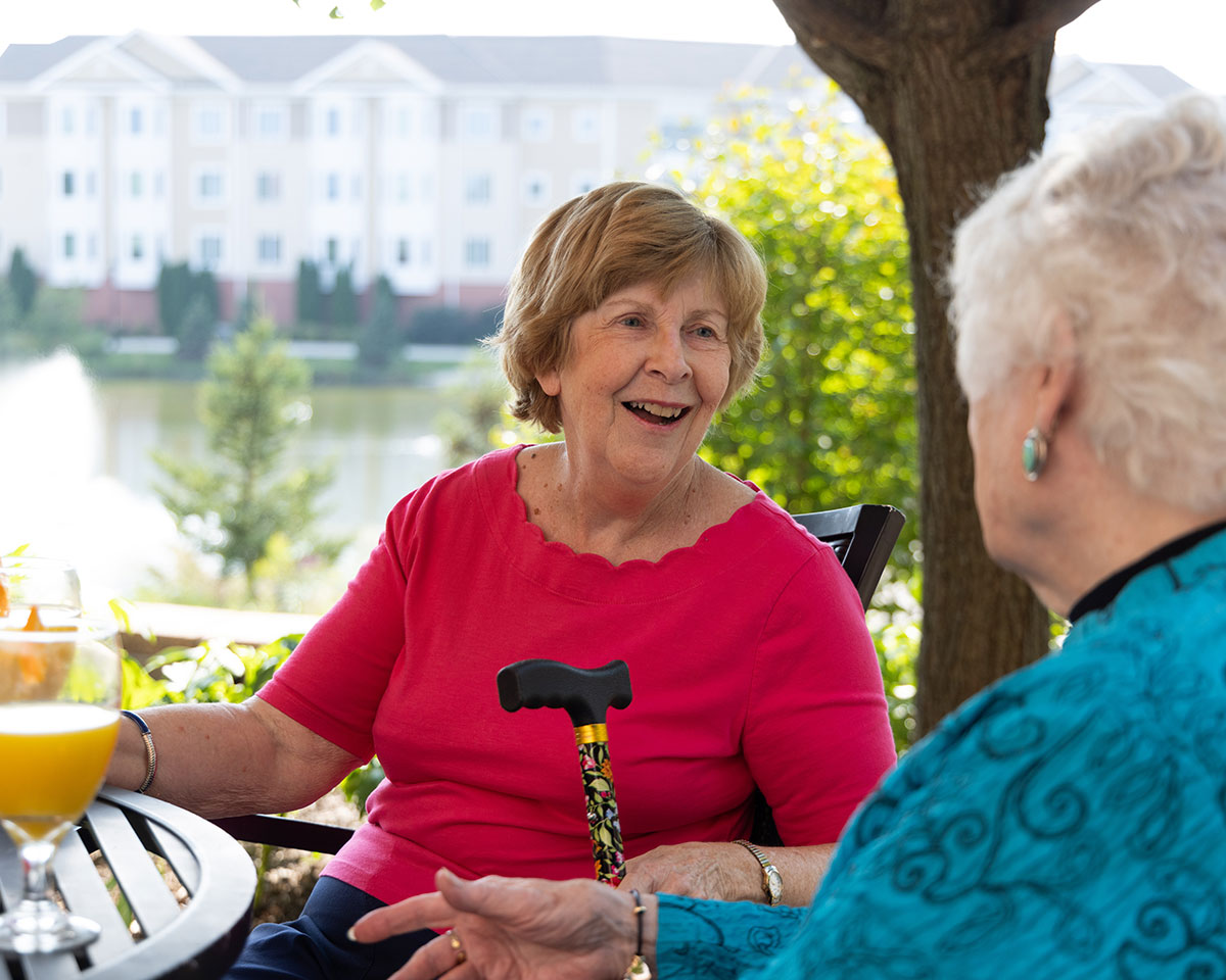 Memory care patient having breakfast outdoors with a friend at The Moorings of Arlington Heights