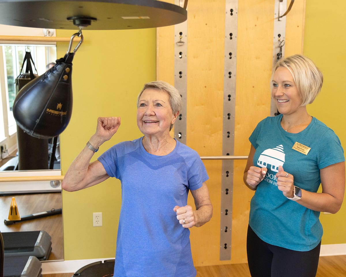 Rehabilitation patient working out with a trainer using a punching bag at The Moorings of Arlington Heights