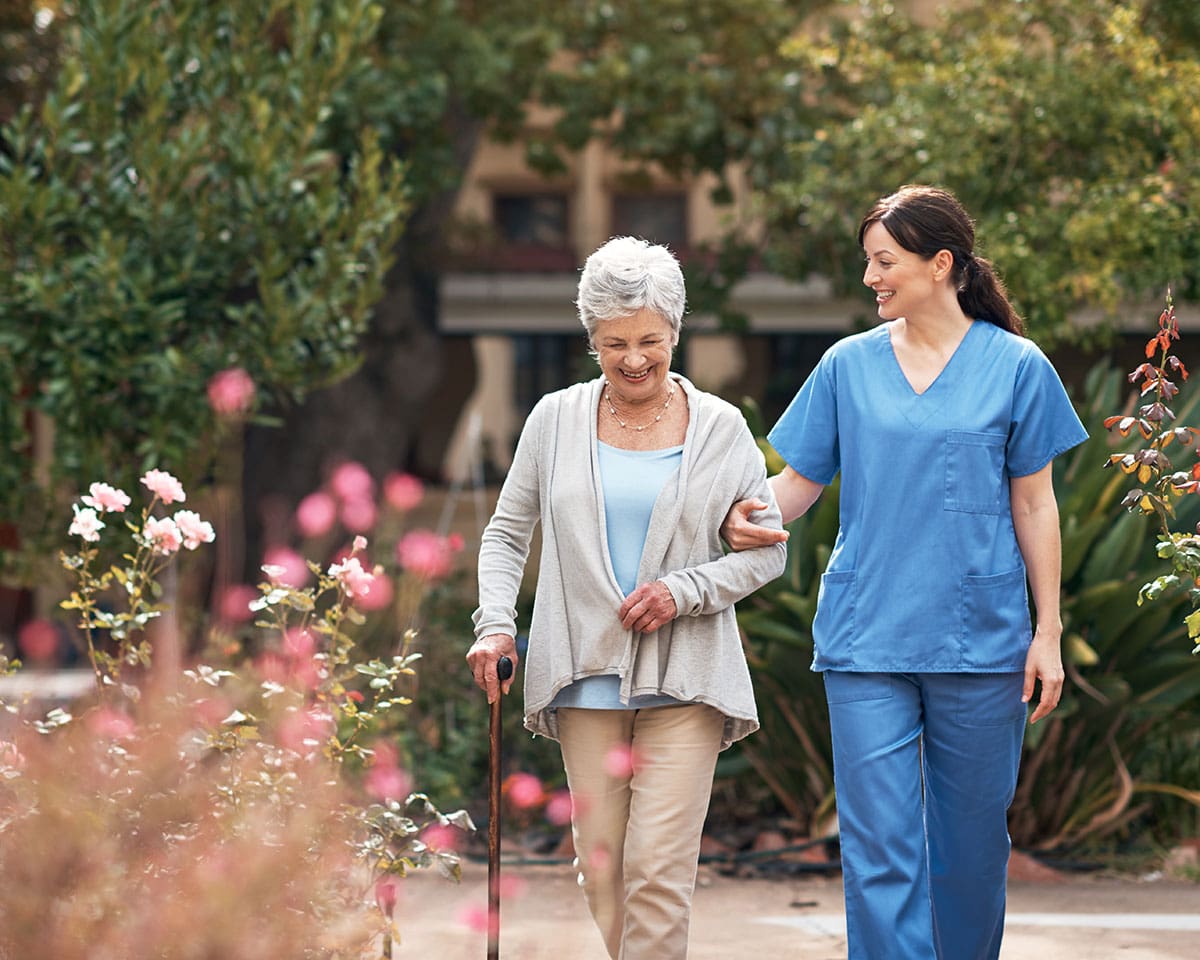 Senior woman walking with her caregiver while enjoying a respite stay the The Moorings of Arlington Heights