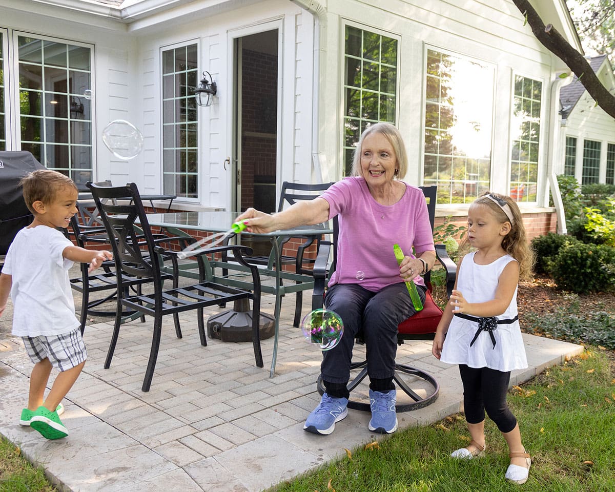 Resident playing with her grandchildren outside her home at The Moorings of Arlington Heights