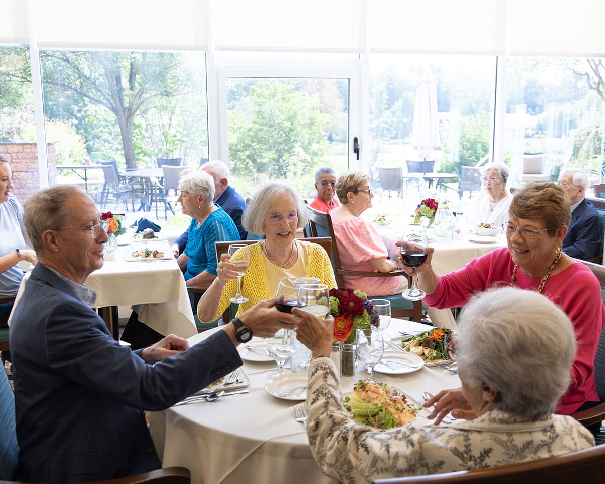 Two resident couples enjoying a meal in the dining room at The Moorings of Arlington Heights