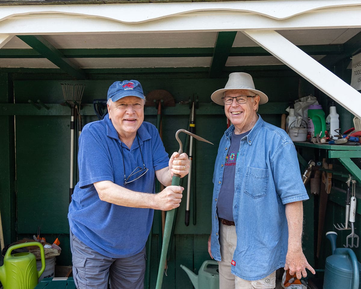 Two senior men gathering gardening tools from a shed at The Moorings of Arlington Heights