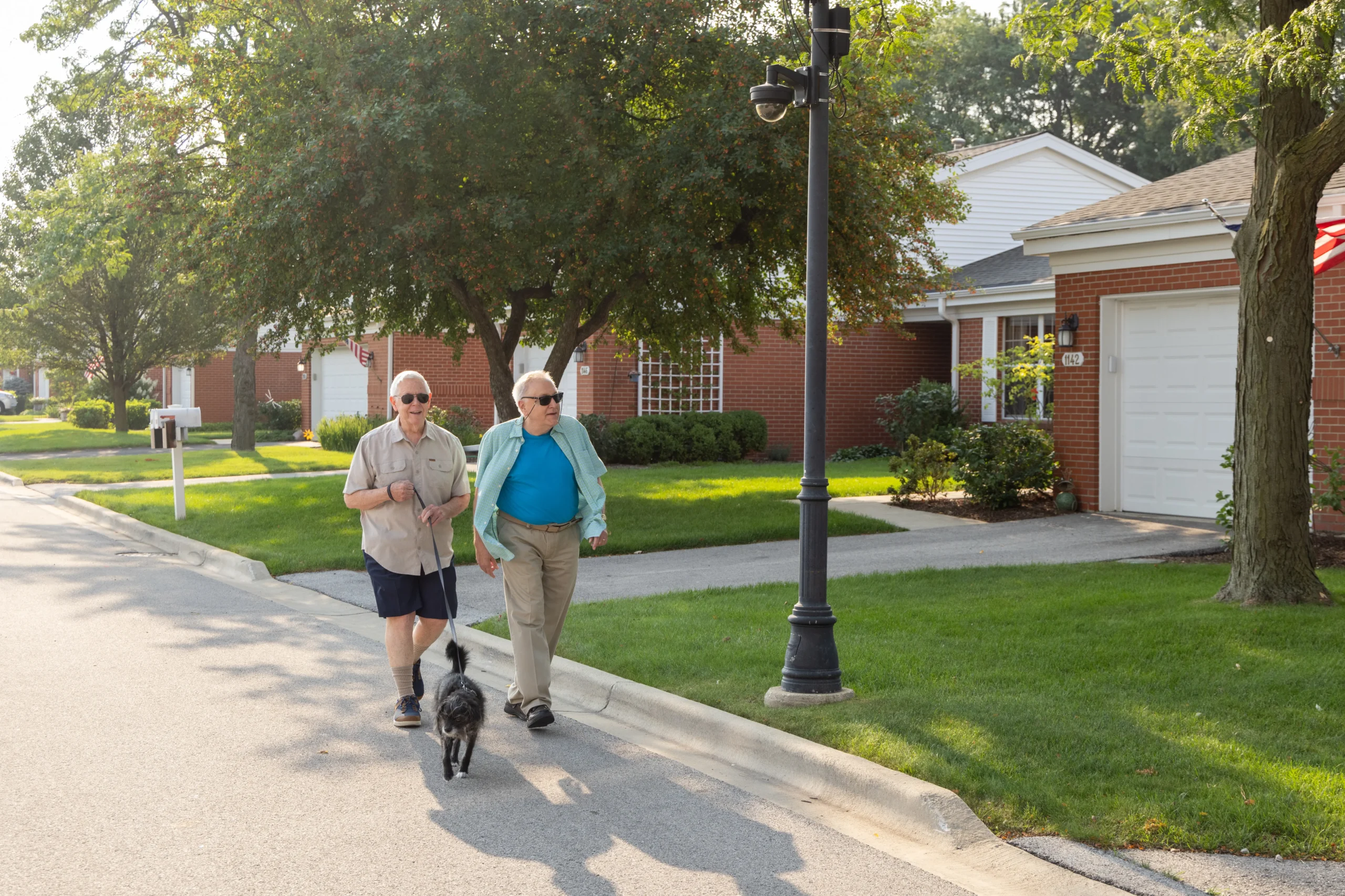 Two seniors walking dog at The Moorings of Arlington Heights