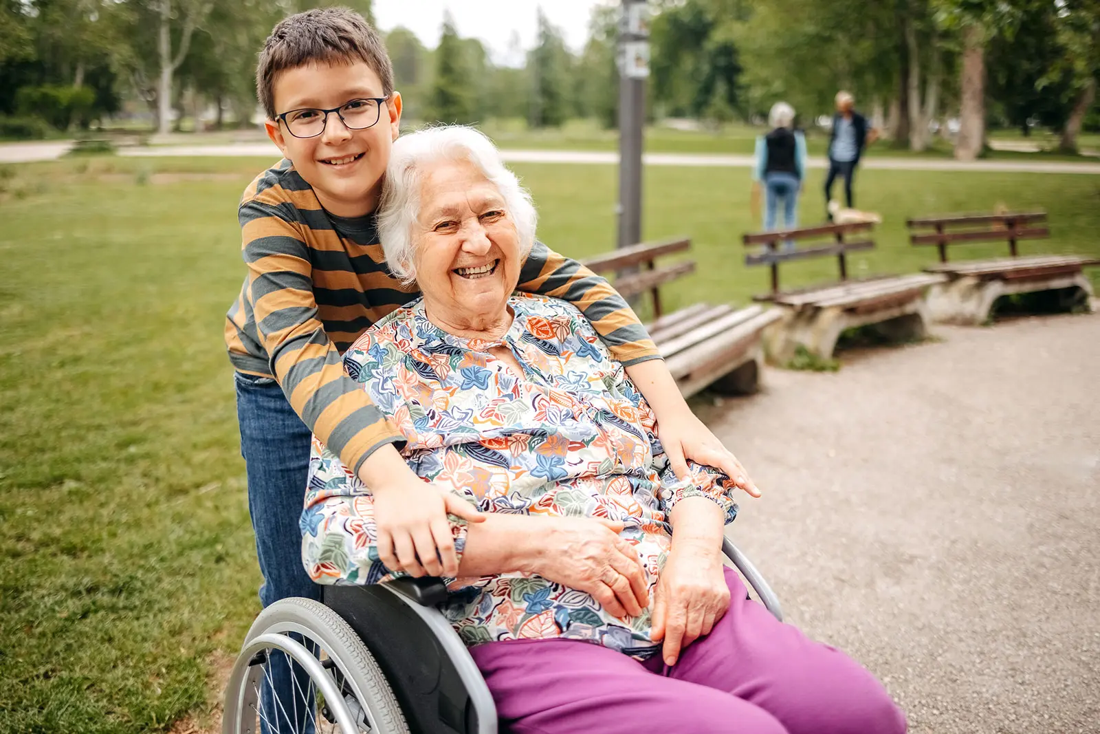 Senior woman in a wheelchair with her grandson hugging her
