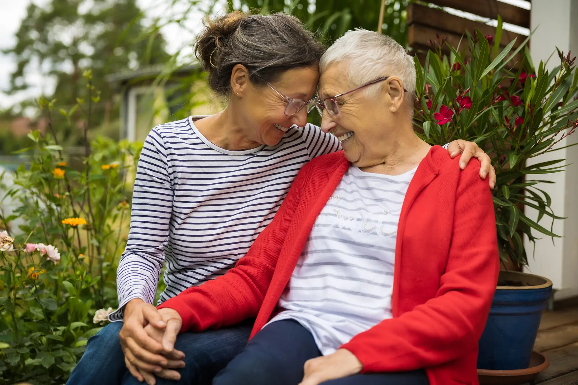 senior woman sitting outdoors with her caregiver