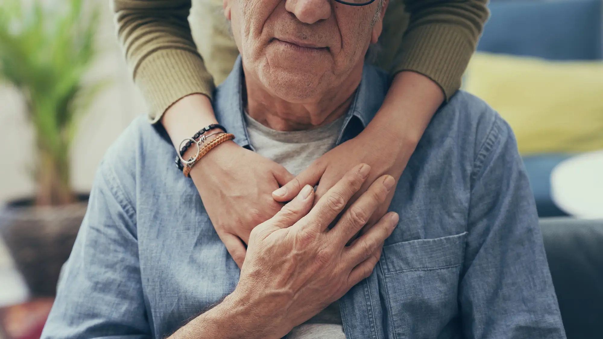 close-up of a caregiver's hands as she comforts a senior man