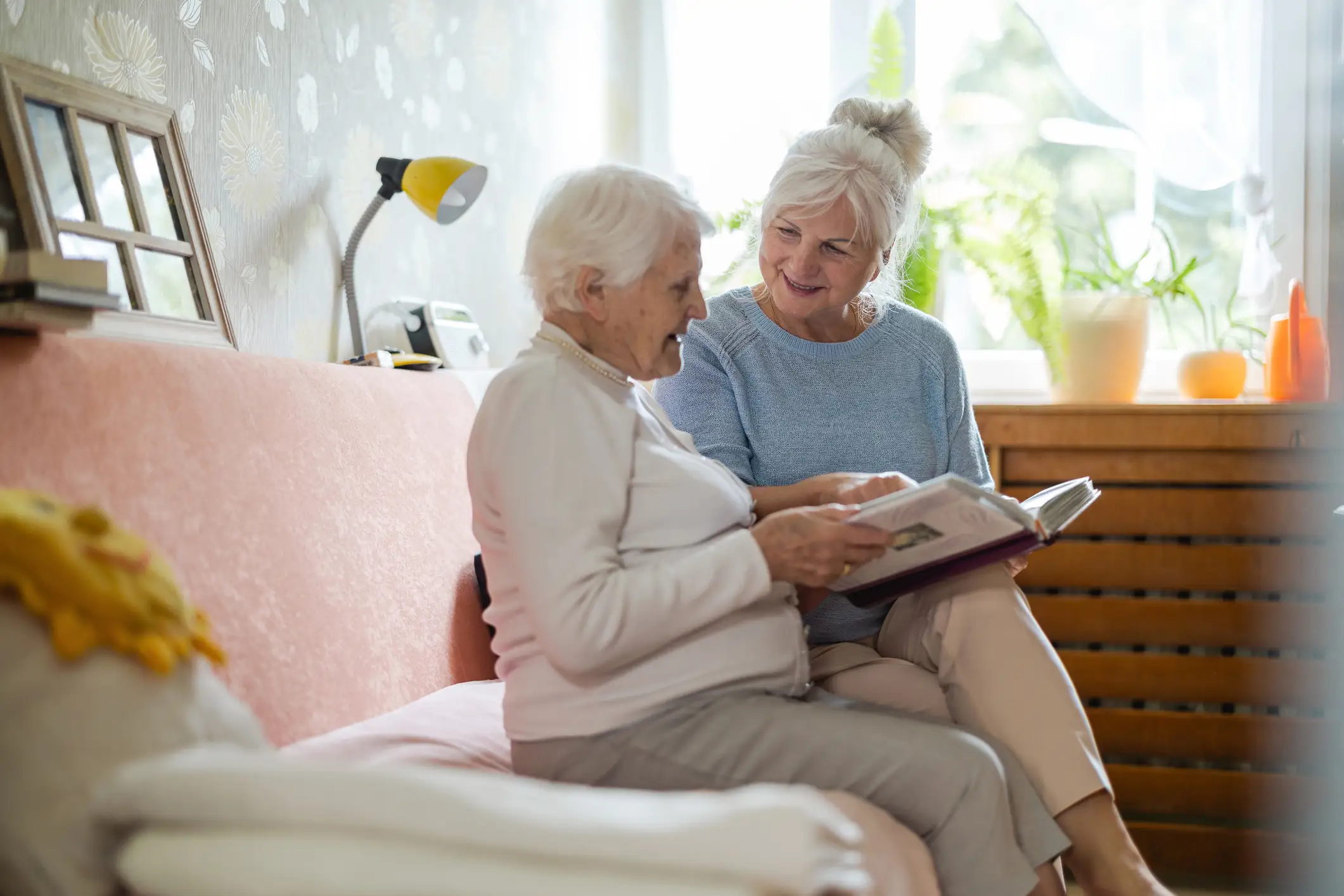 Senior woman reading a book with her adult daughter, when is it time for memory care Evanston, IL