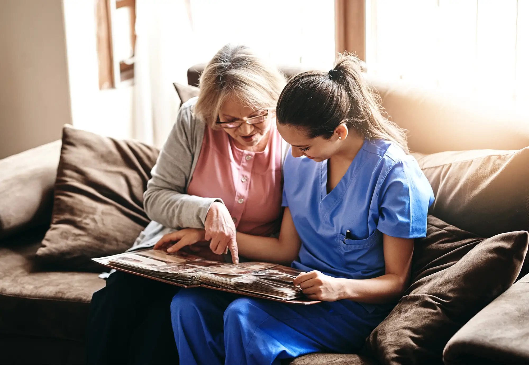 Senior woman looking at a photo album with her caregiver