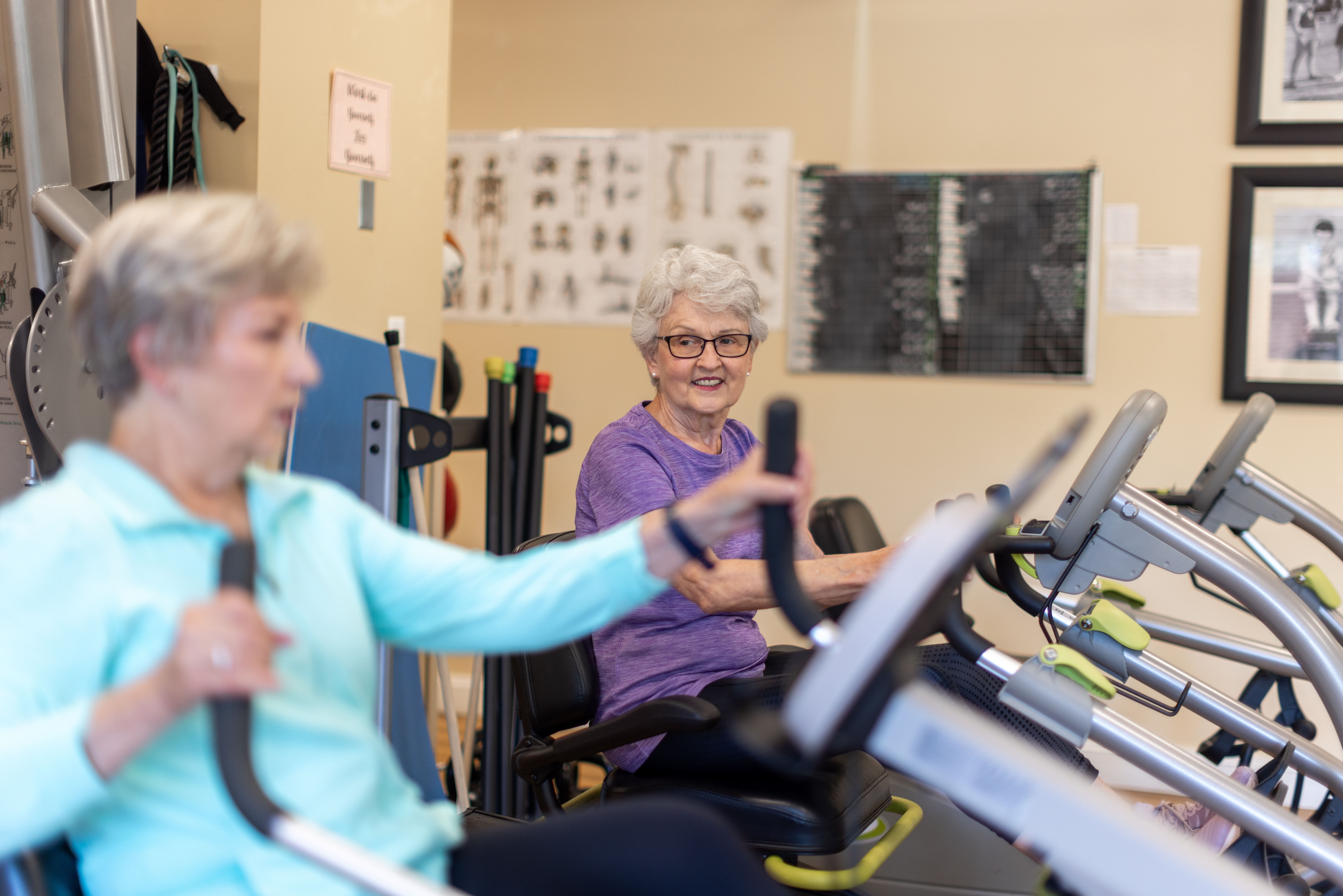 Two resident women working with a trainer in the fitness center at Lake Forest Place