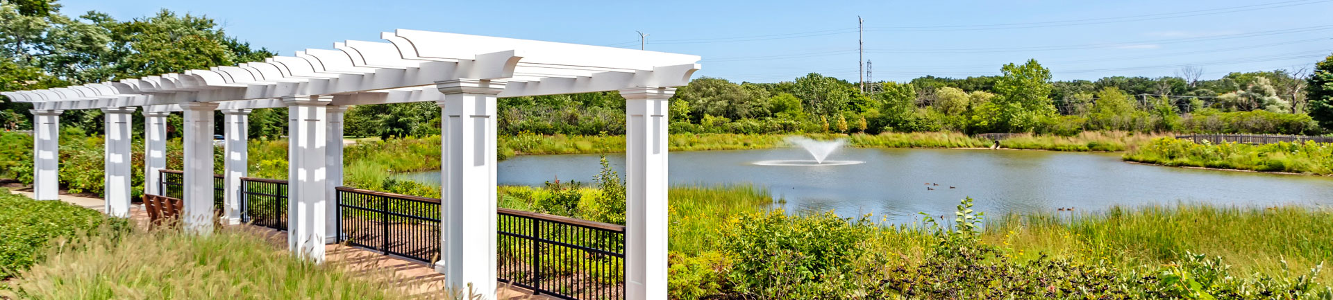 a covered walkway next to a pond with a fountain