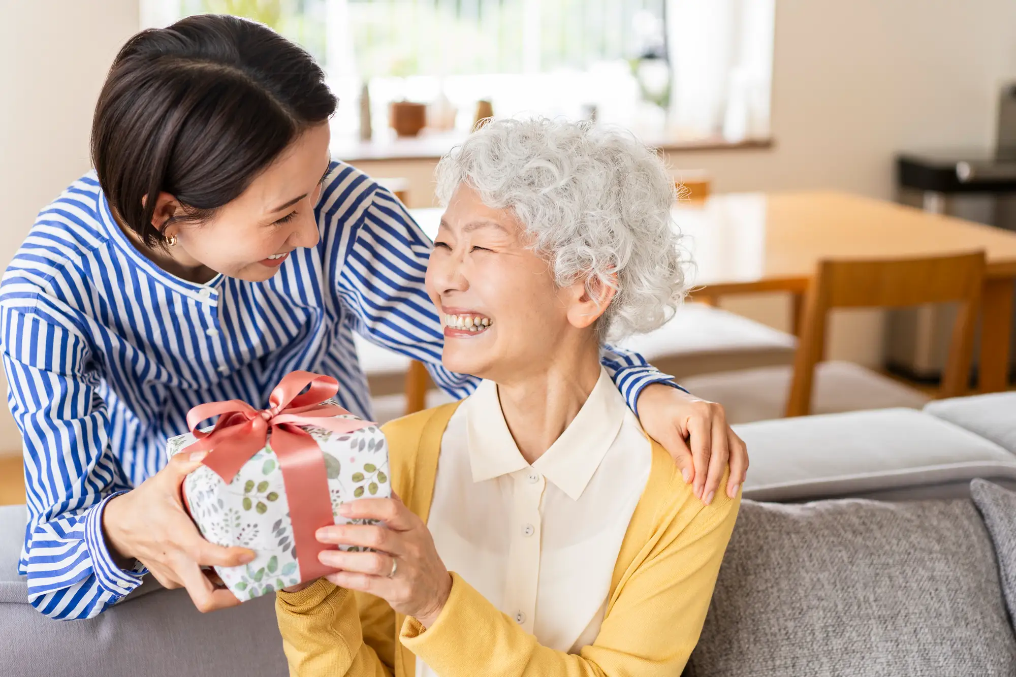woman giving her senior mother a gift