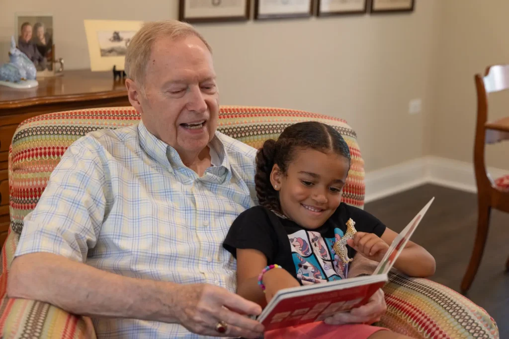 Grandfather reading book with granddaughter on his lap