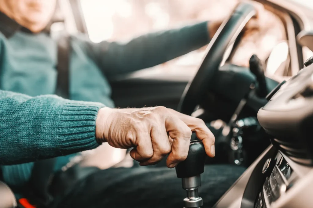 Close up of senior man holding one hand on gearshift and other on steering wheel
