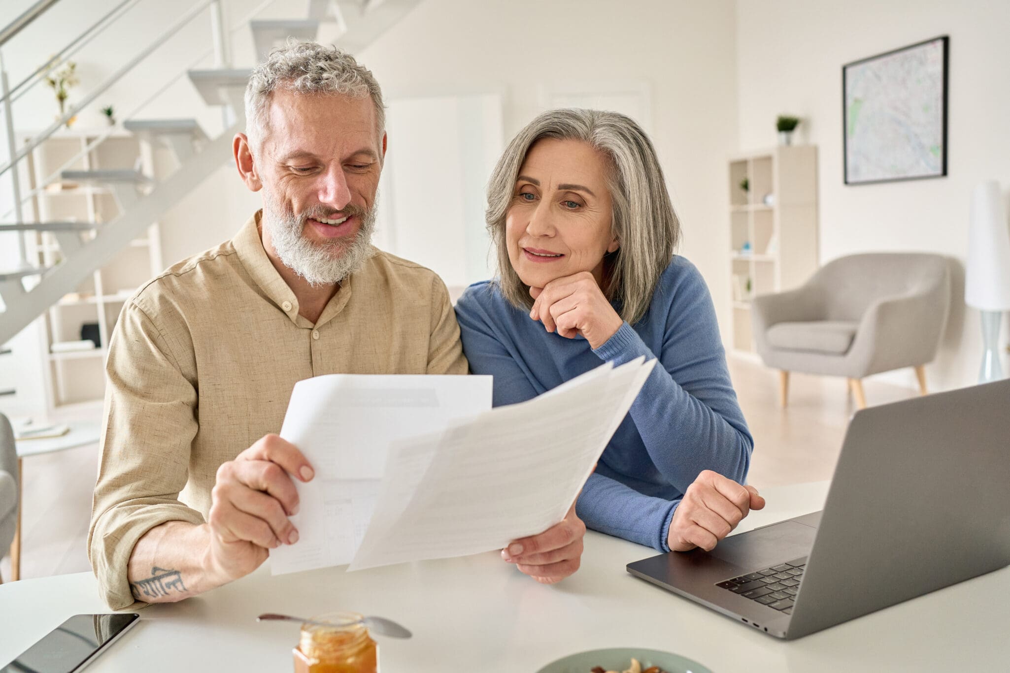 Senior couple view pre-retirement checklist on computer with financial documents in hand