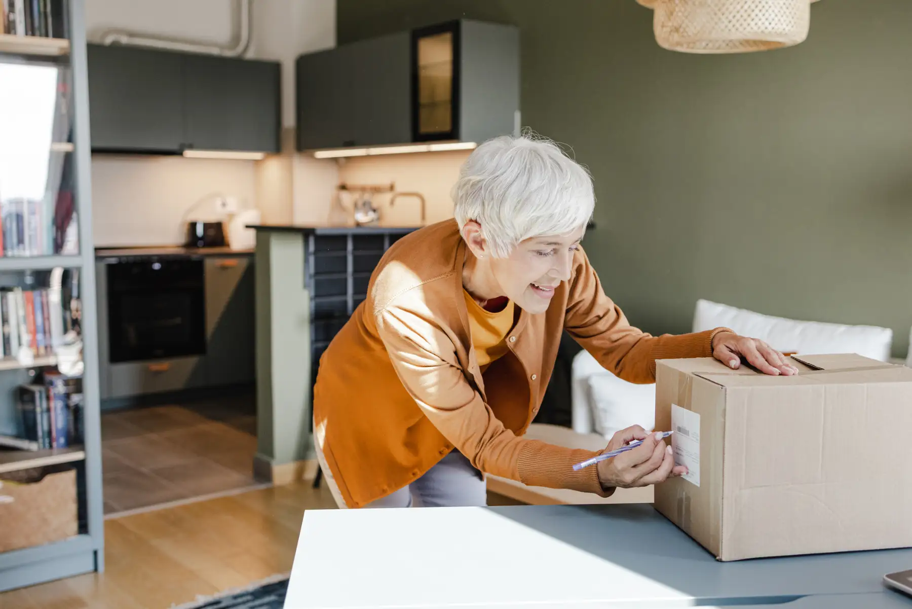 iStock-1389706759 a senior woman writing on the label of a moving box