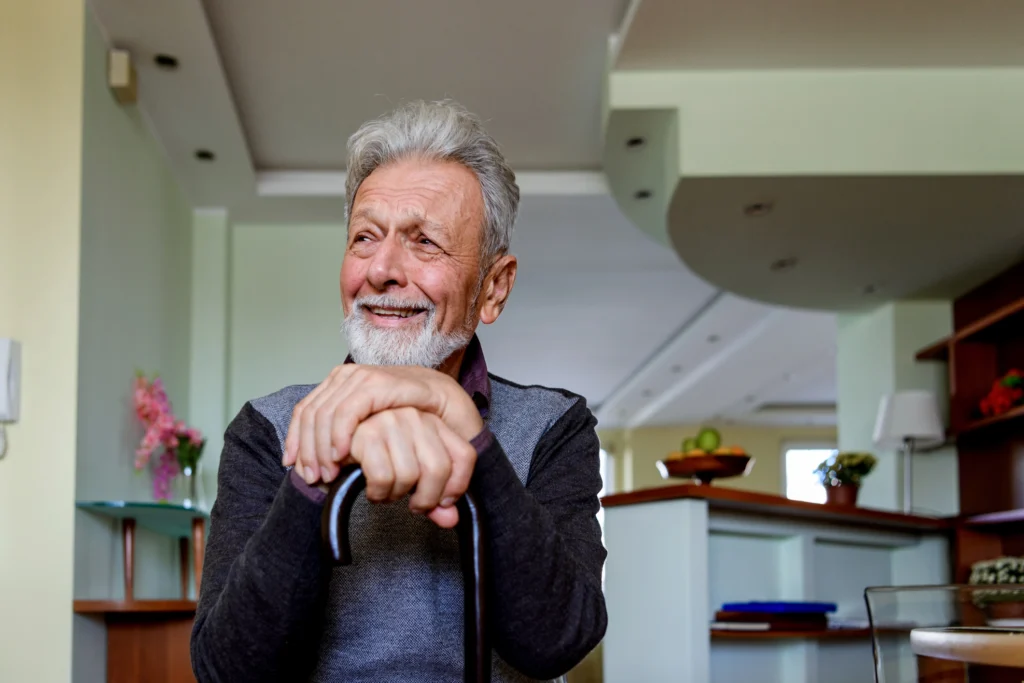 senior man sitting with hands resting on cane