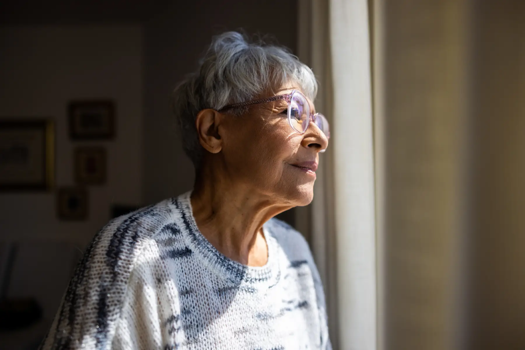 iStock-1472634406 a senior woman looking out the window in thought