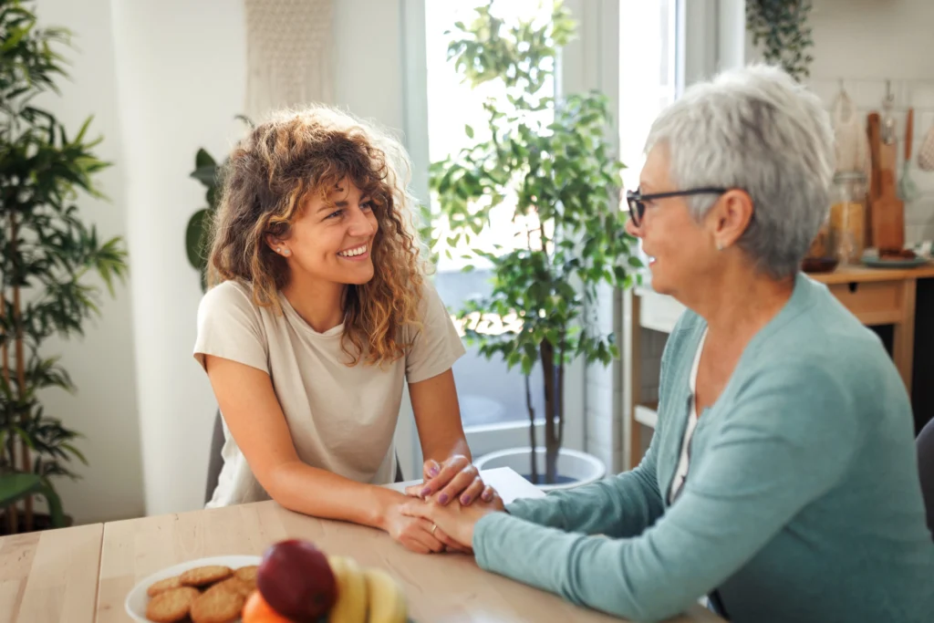 adult woman holding senior woman's hands