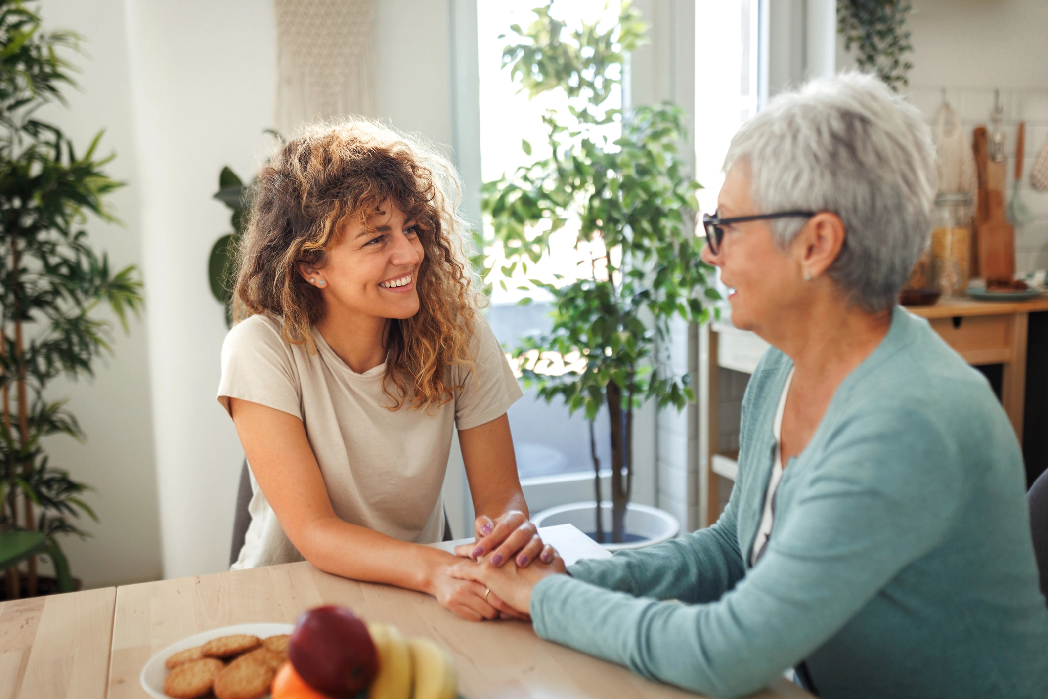 adult woman holding senior woman's hands
