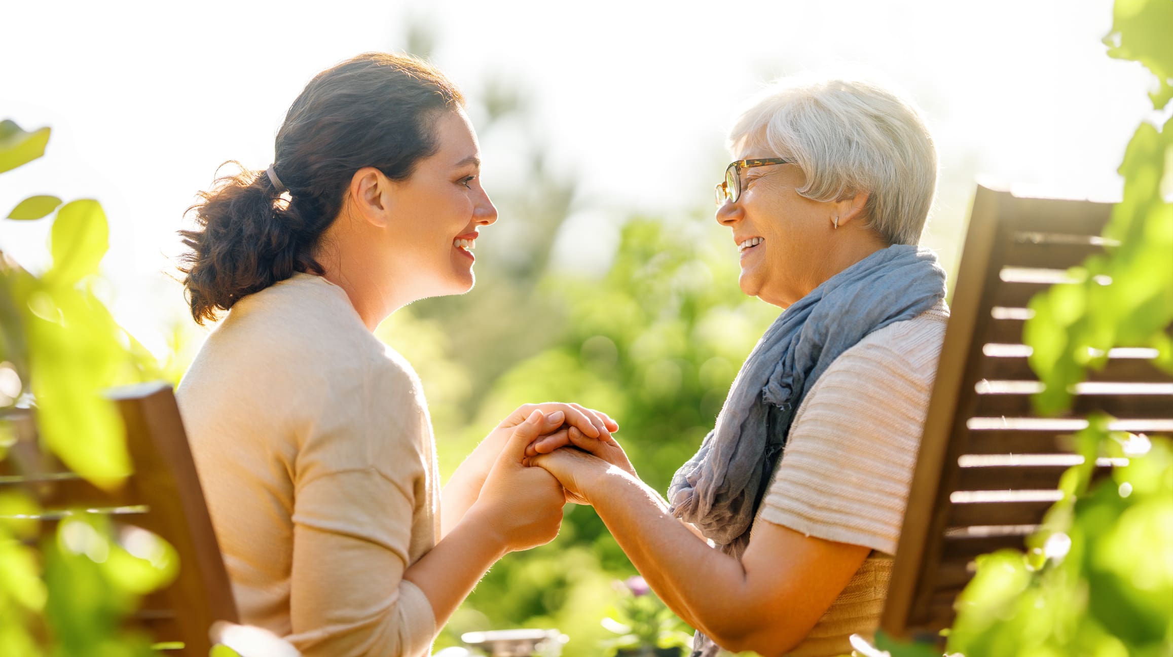 Senior woman and adult woman holding hands in garden