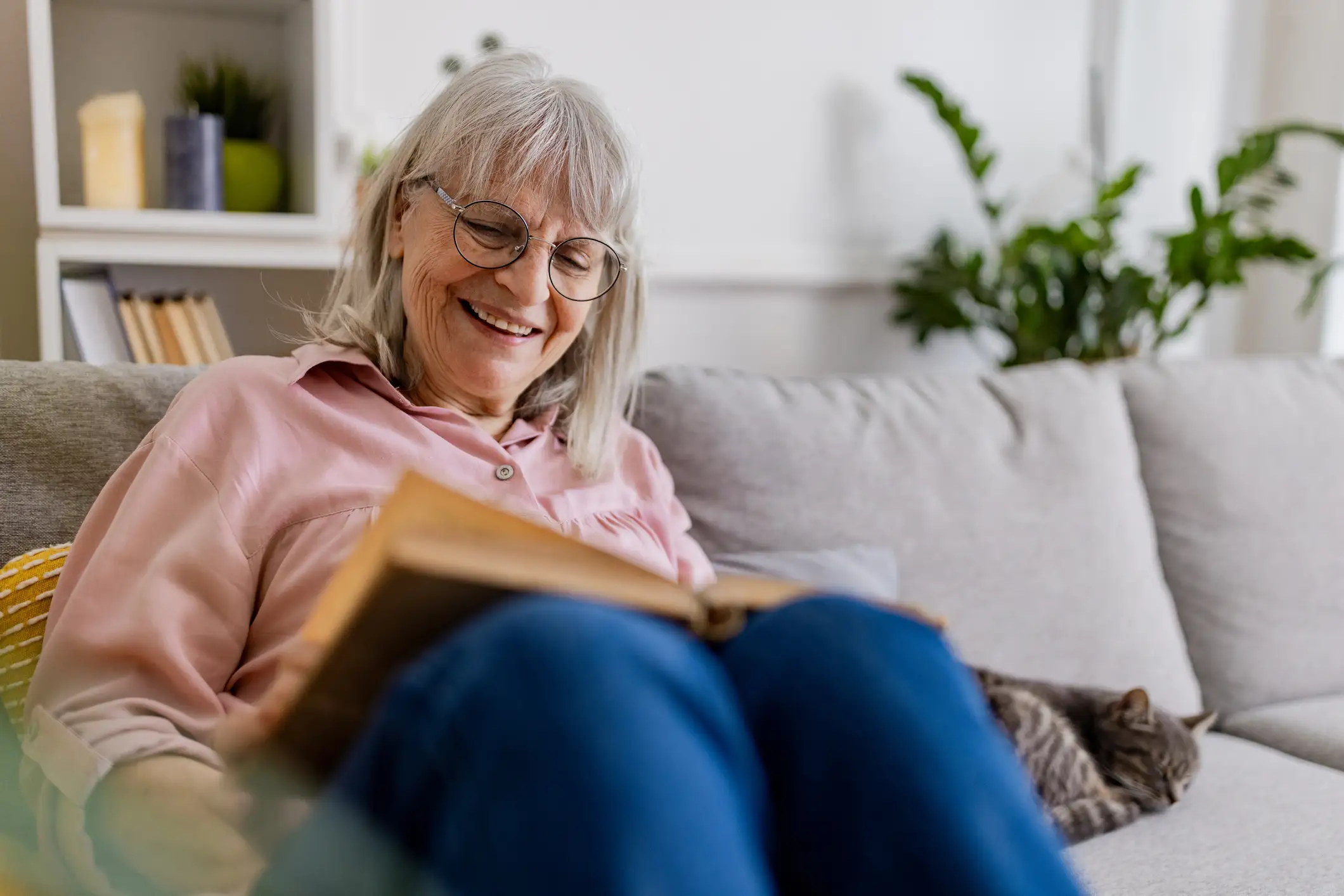 Senior woman reading in her apartment on the sofa