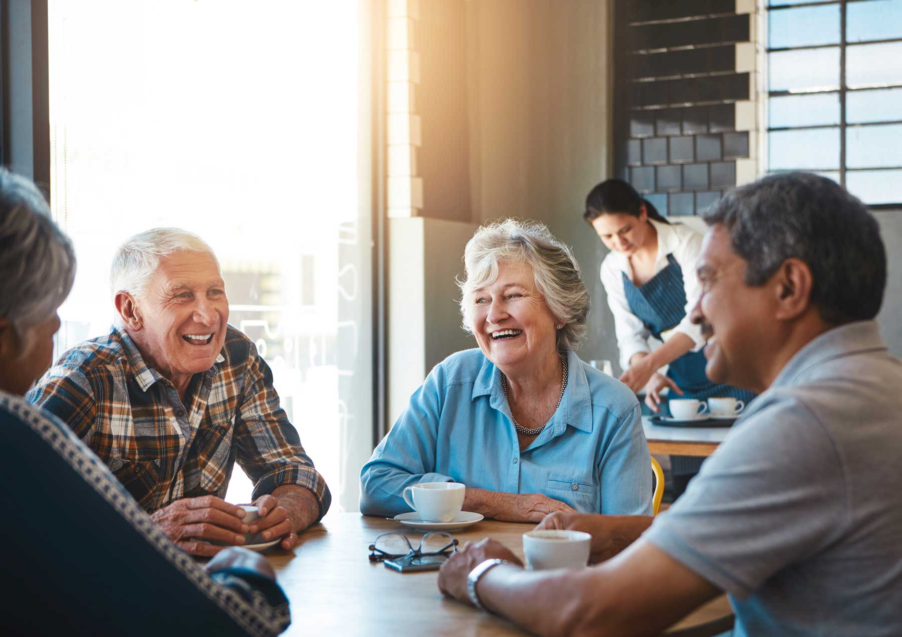 iStock-648845186 a group of senior friends sitting at a cafe talking and laughing