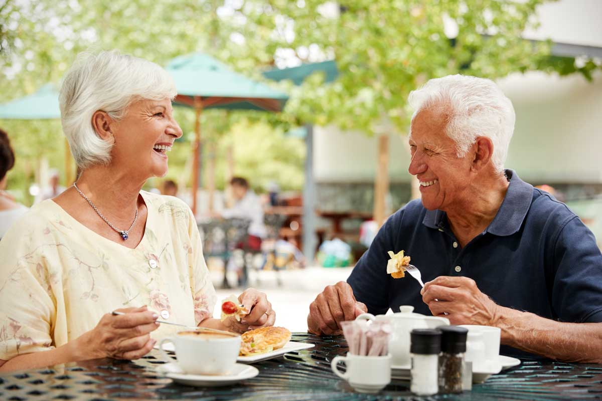 a senior couple enjoying their breakfast outside on the desk