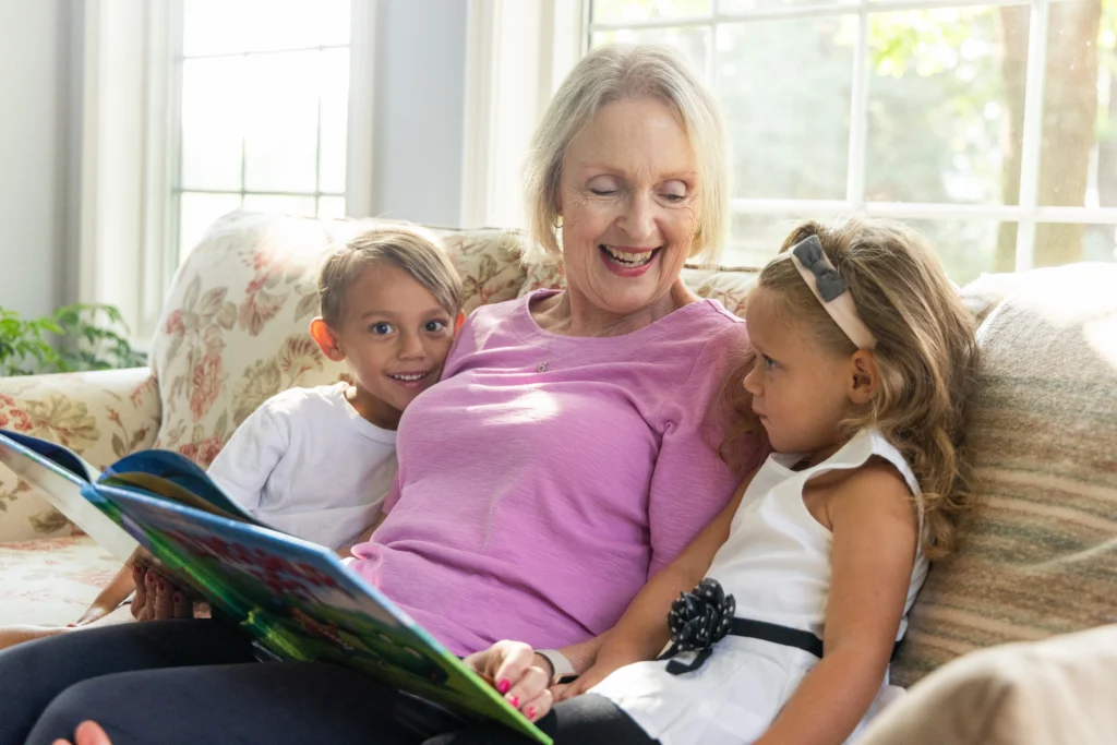senior woman at The Moorings of Arlington Heights reading book with grandchildren
