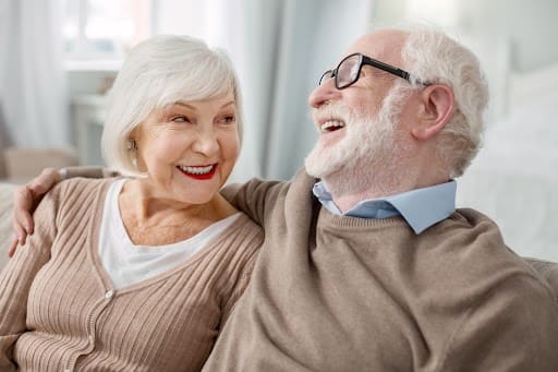 senior couple laughing together on the couch senior couple laughing together on the couch