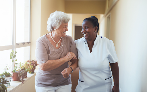 senior woman with caregiver walking down the hallway