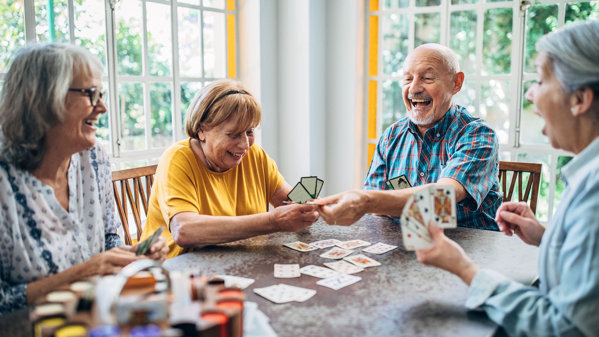 Old people having fun playing cards in nursing home Group of senior friends playing cards and laughing together