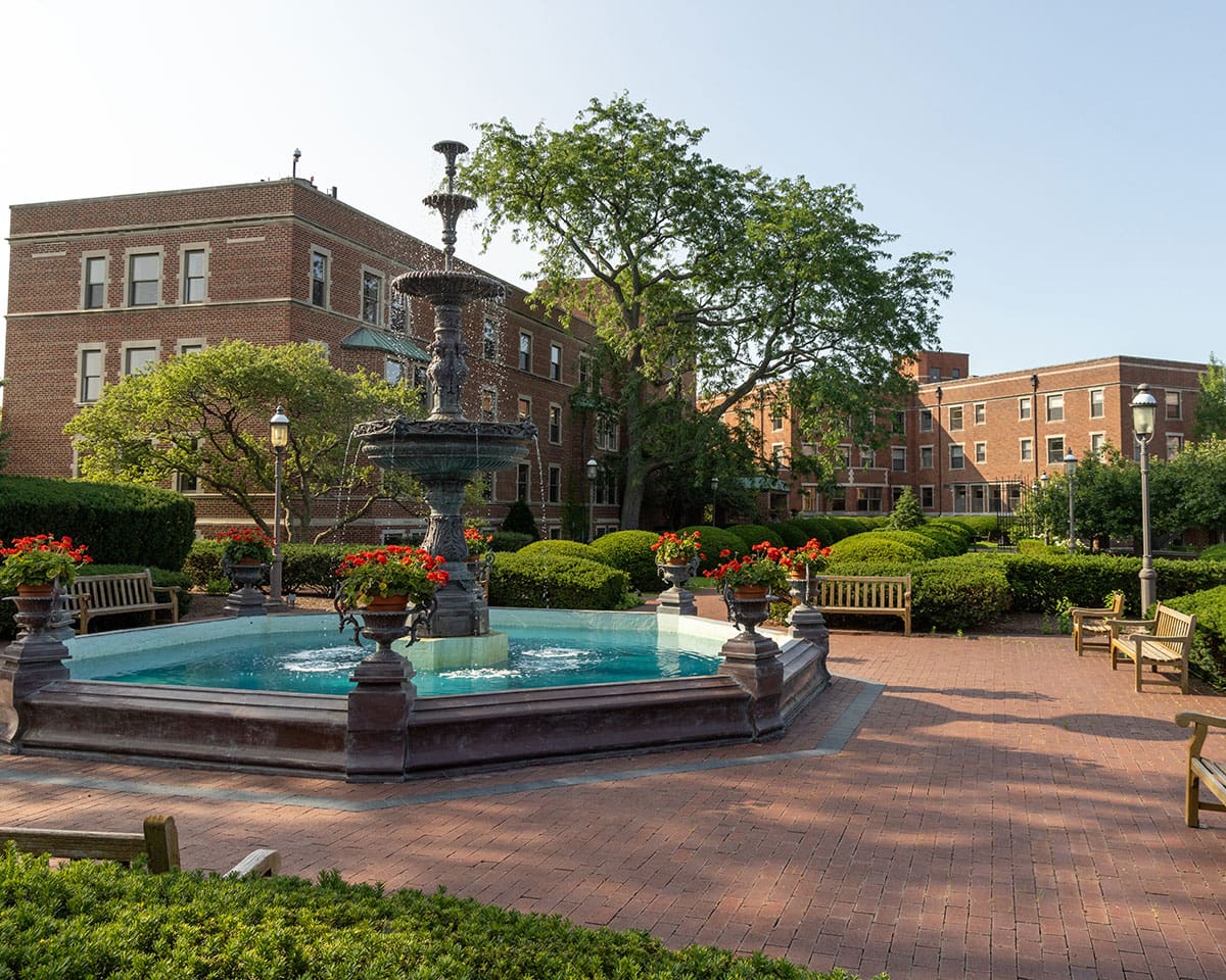 Beautiful outdoor photo of a fountain with benches around it and Westminster Place apartments in the background