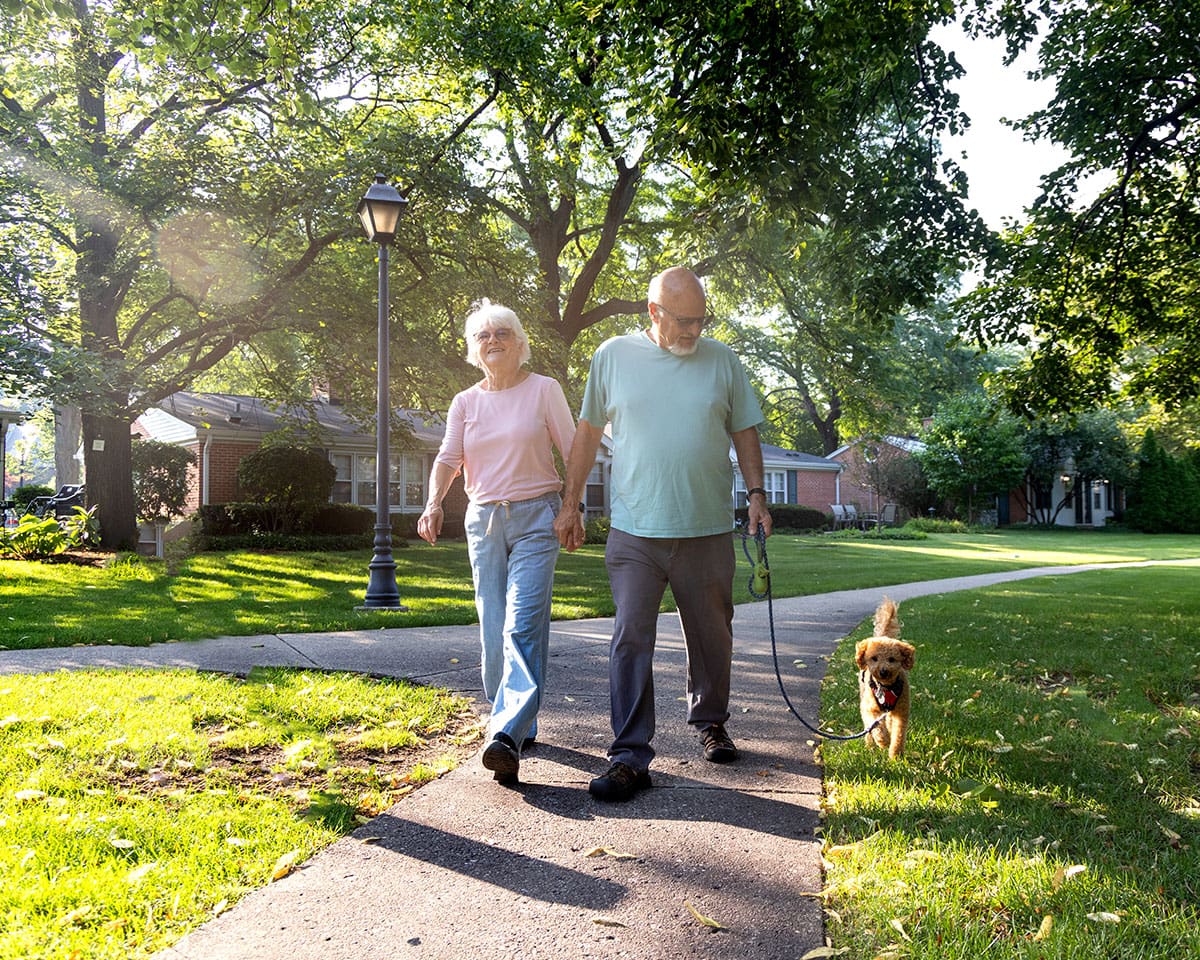 Senior couple walking their dog on a beautiful path at Westminster Place
