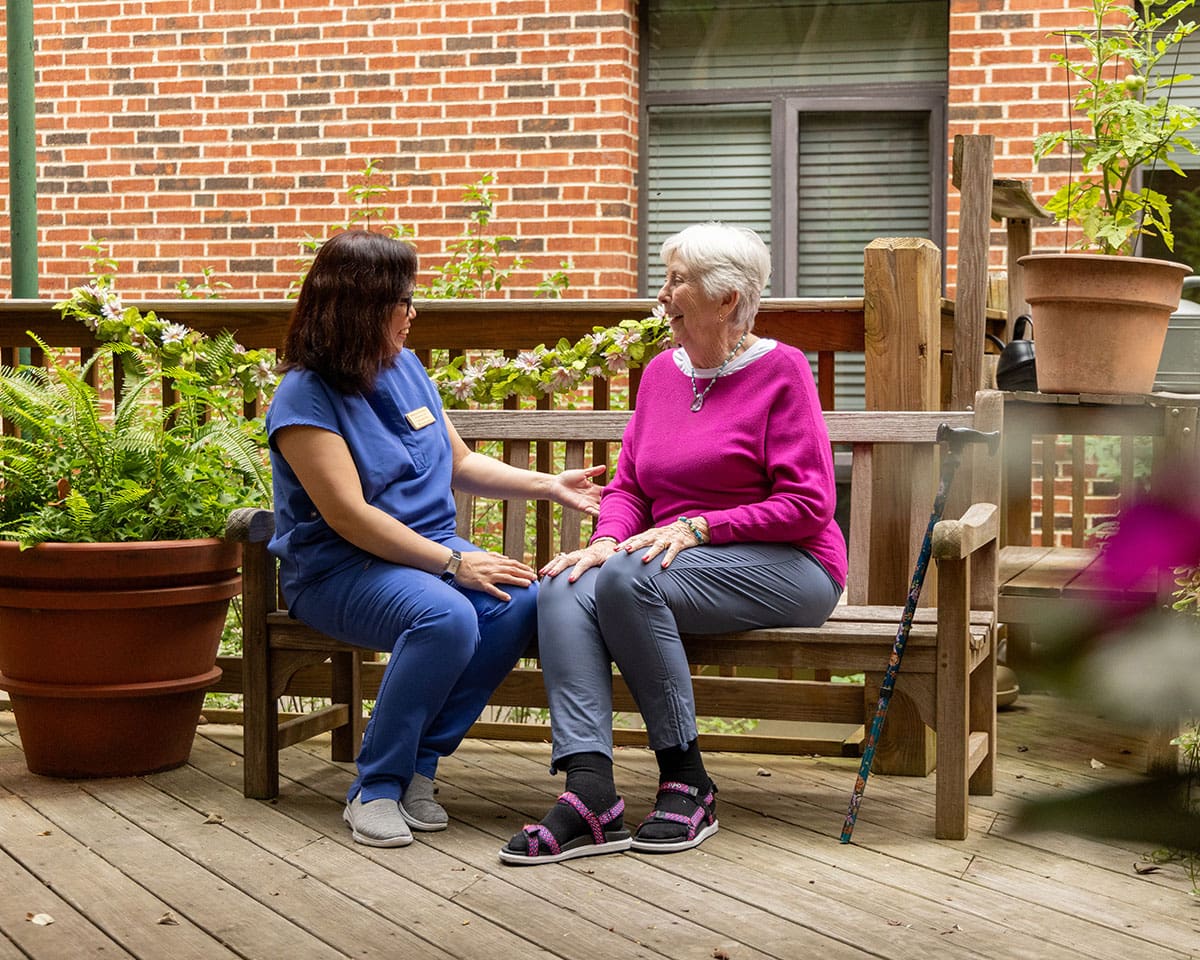 Caregiver sitting on a bench outdoors with a resident at Westminster Place