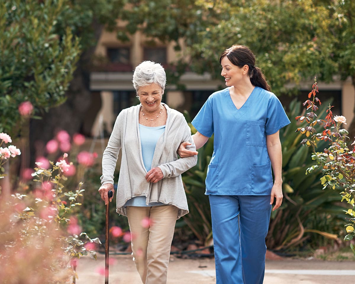 Senior woman walking outdoors with her caregiver at Westminster Place