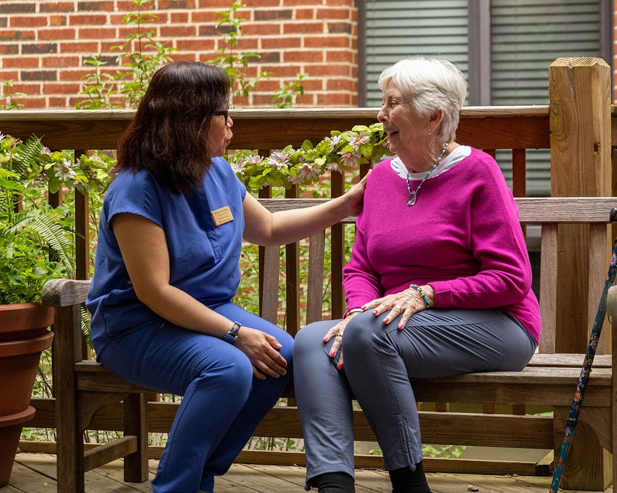 Caregiver sitting on a bench outdoors with a resident at Westminster Place